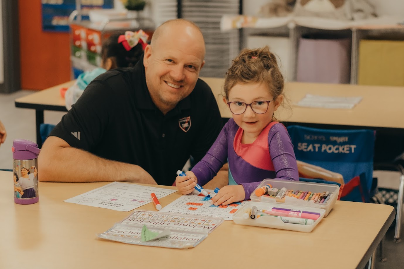 Terry poses with a student working on a coloring project